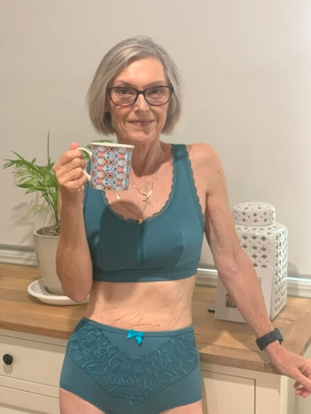 Woman wearing a teal organic cotton bra and knickers holding a mug at home – JulieMay Lingerie